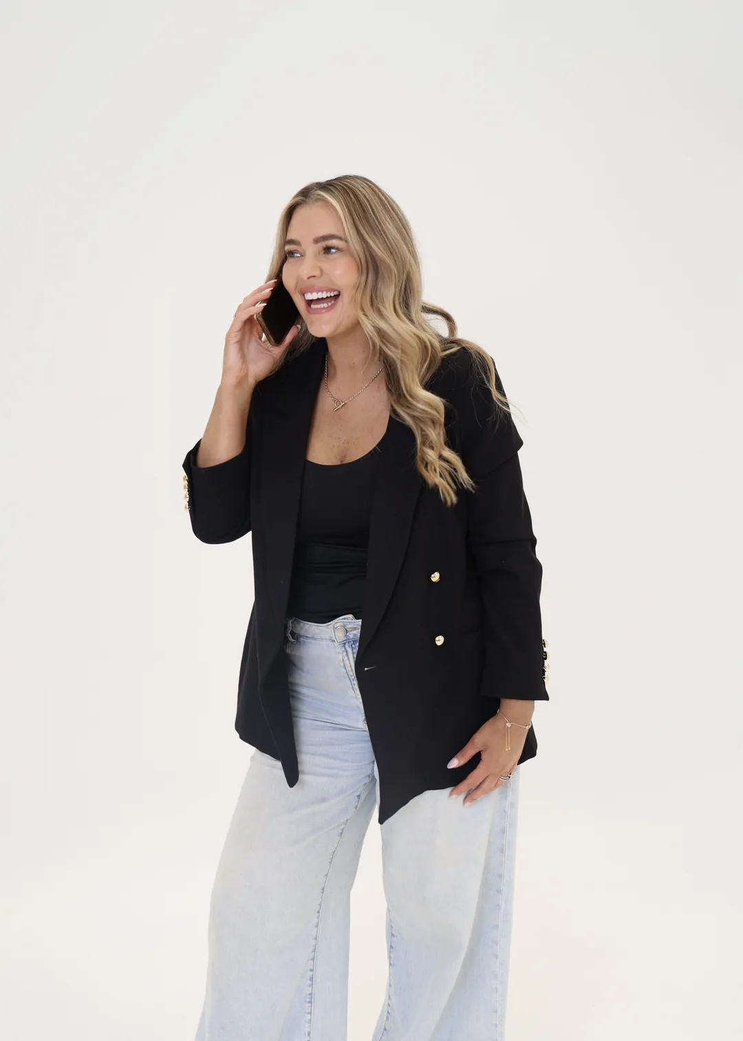 Krystle laughing on the phone in a black blazer