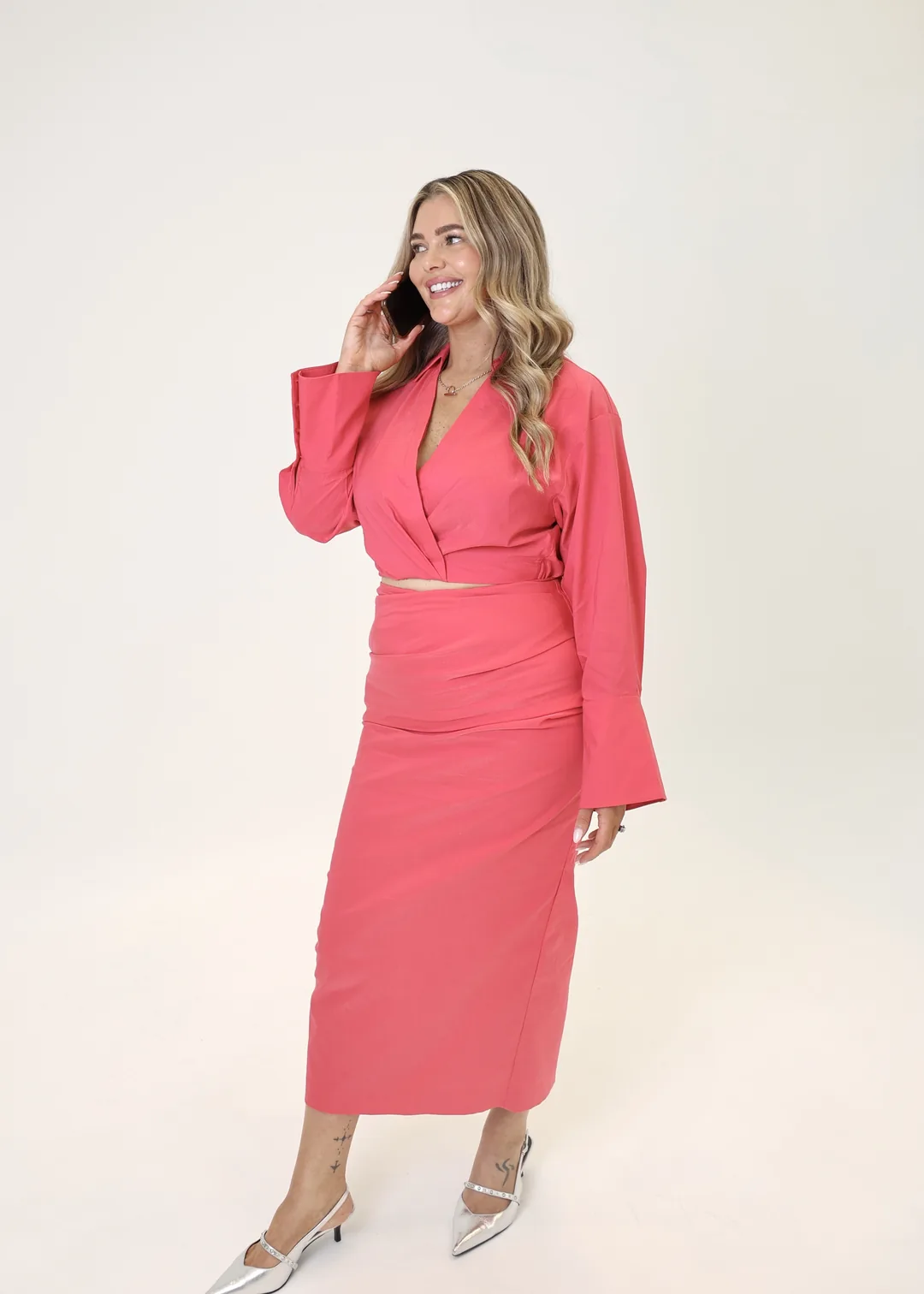 Krystle smiling on the phone in a bright pink suit